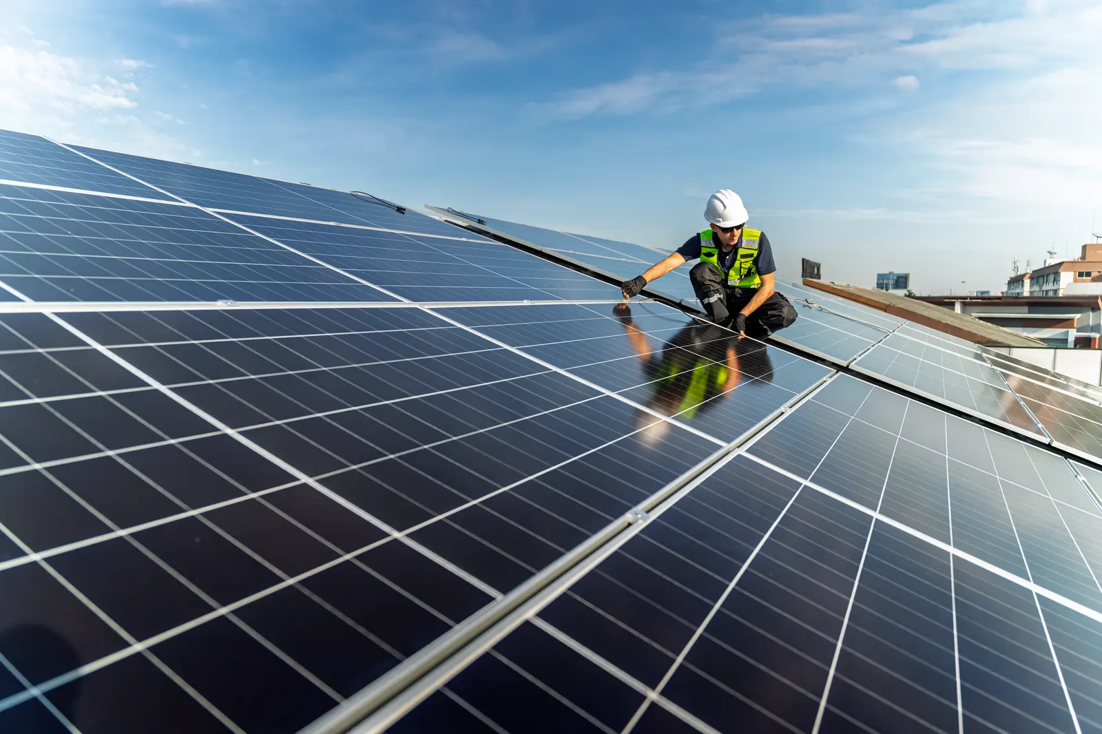 A technician fits a solar panel on a rooftop