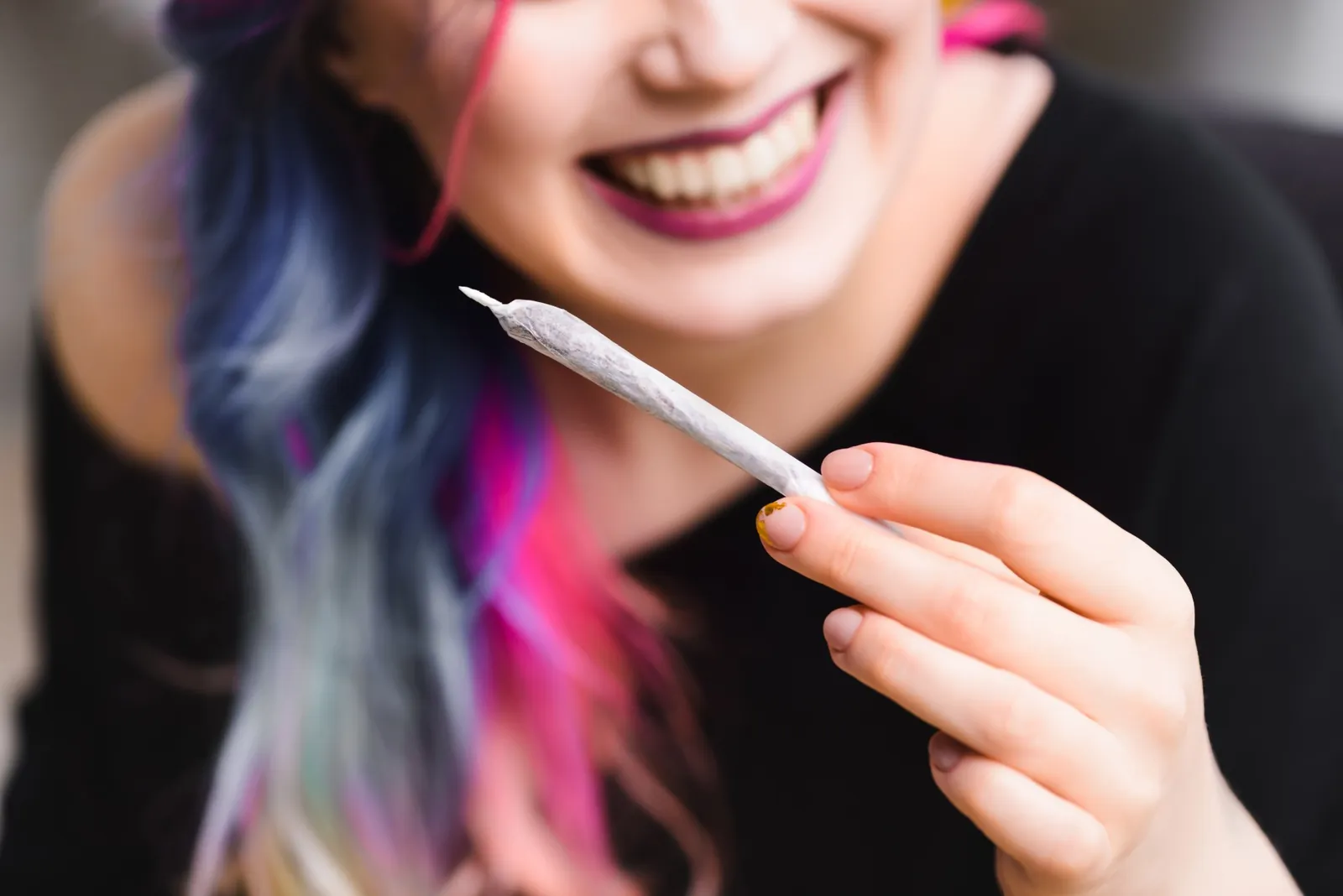 A smiling woman holding a pre-roll