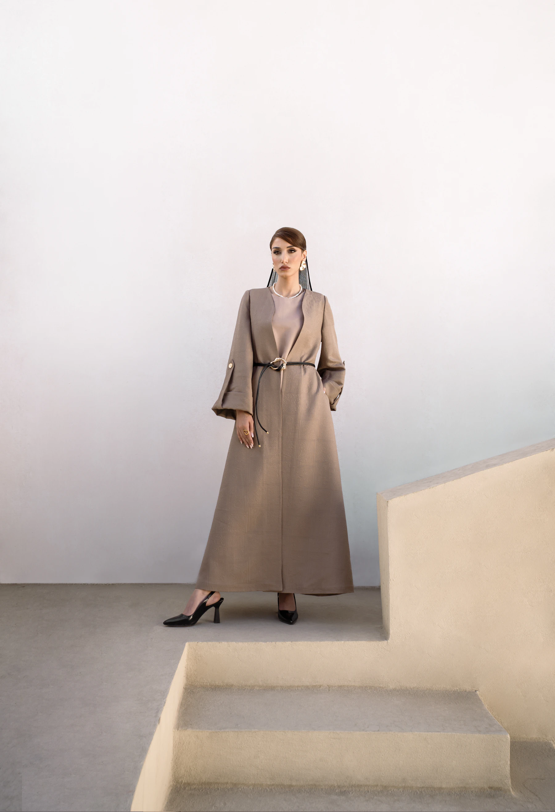Woman in a long camel coat standing on stairs