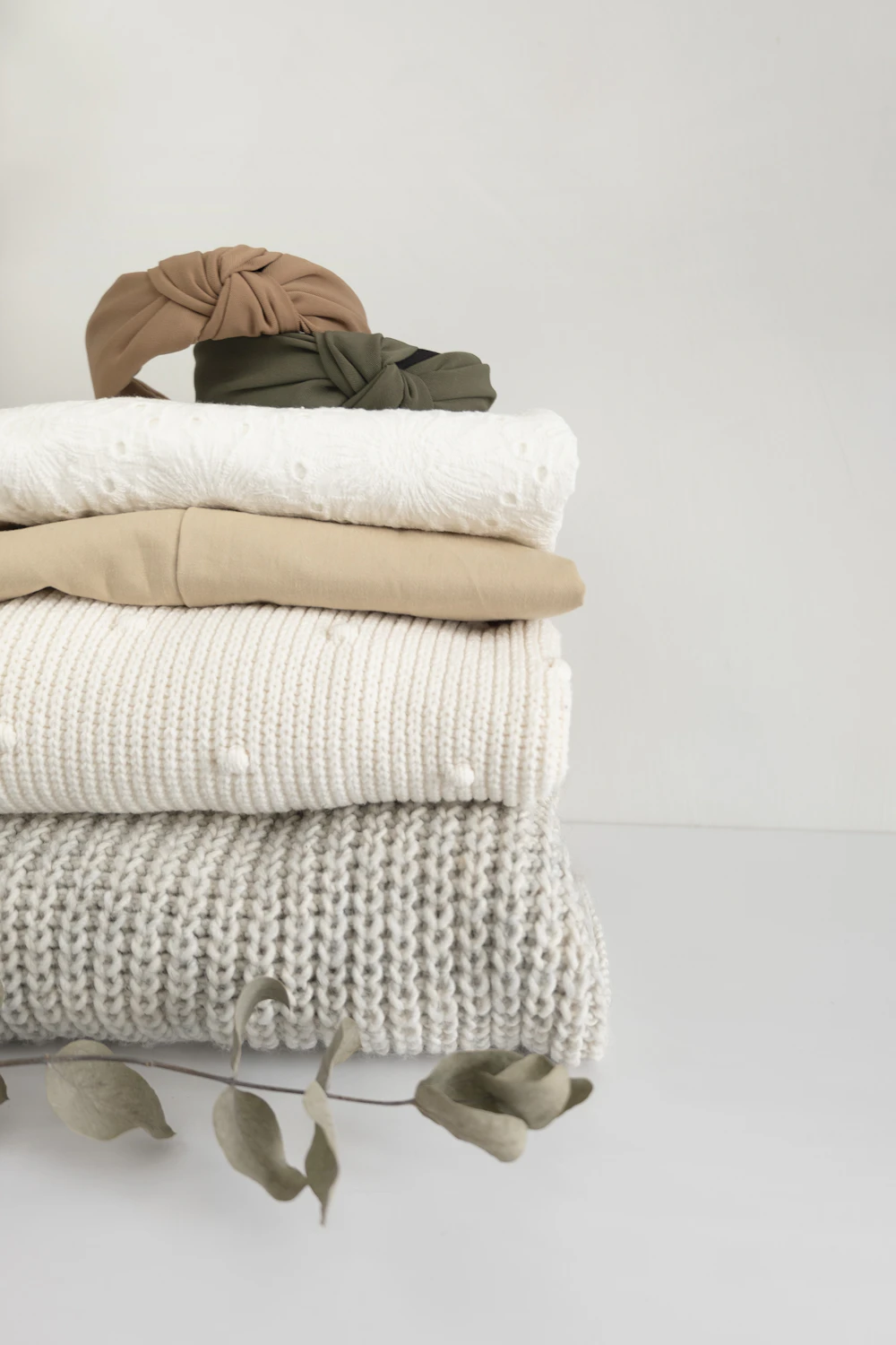 A stack of folded knits in oat and cream