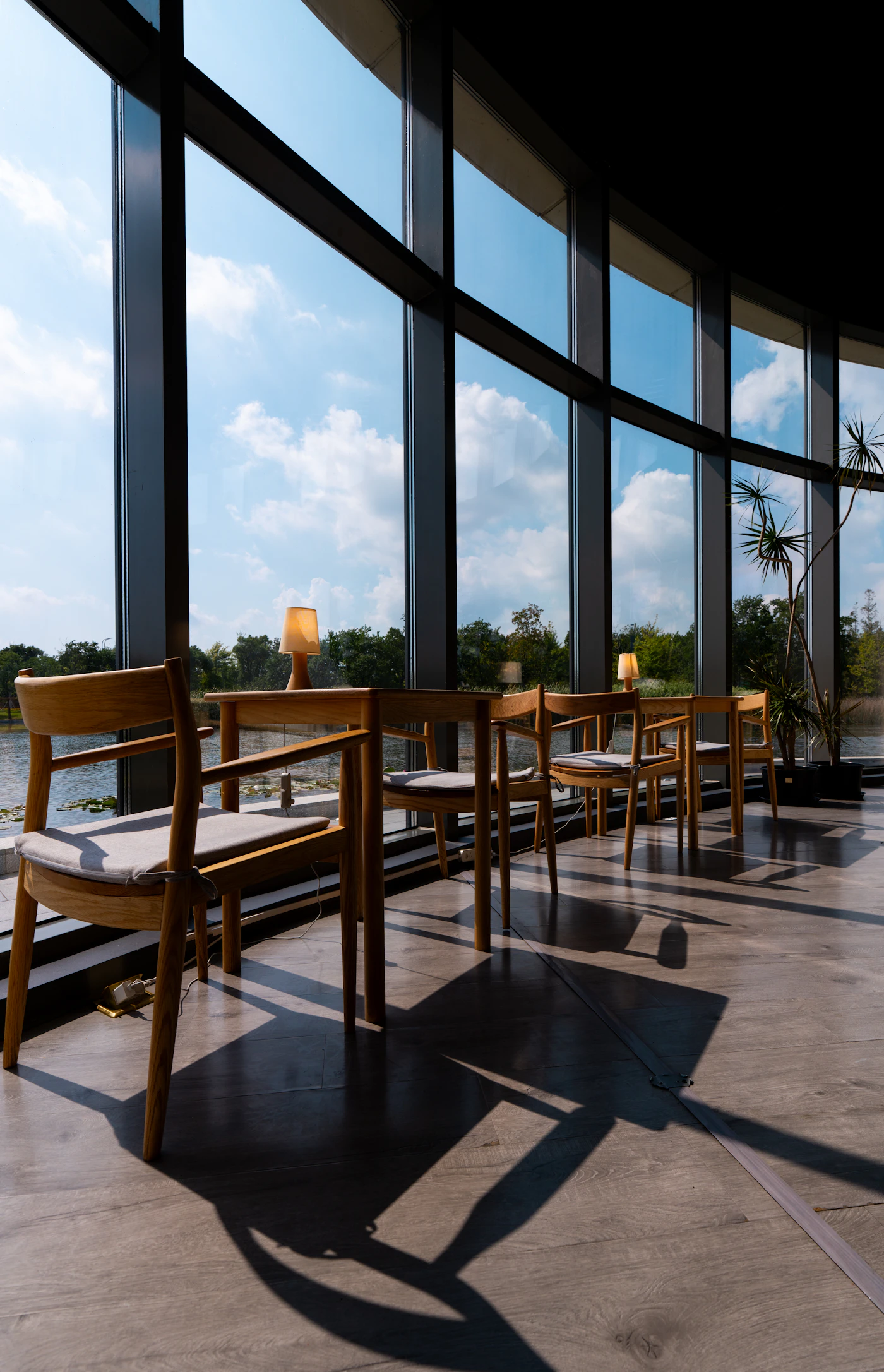 Wooden chairs by tall windows facing a lake