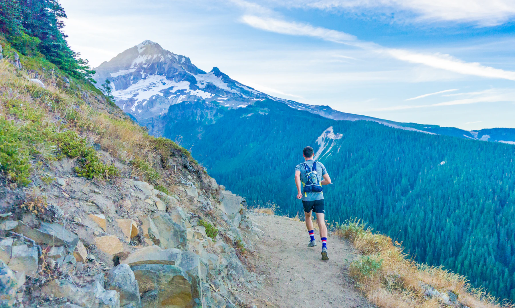 Runner on a ridge trail above a mountain lake