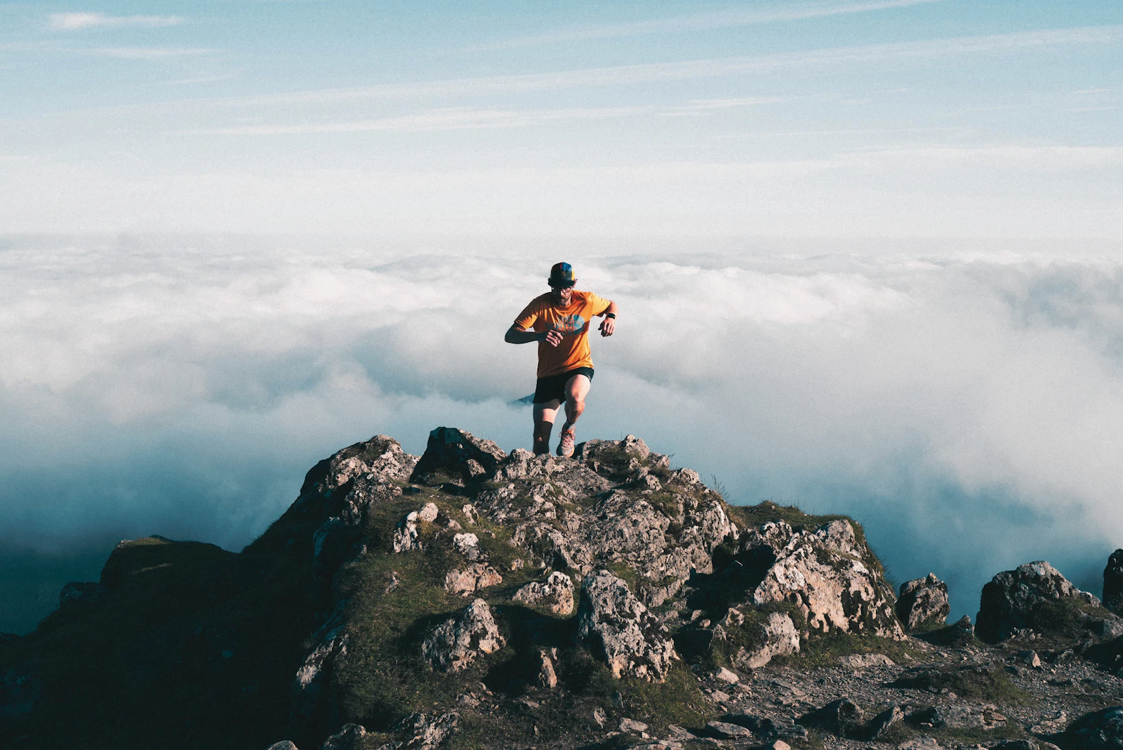 Runner on top of a rocky summit above the clouds
