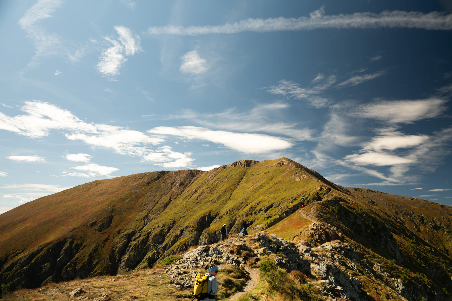 Hikers on a rocky ridge trail under a blue sky