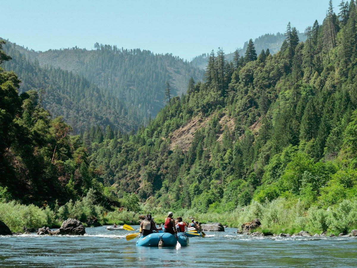 Raft on a wide green river below canyon walls