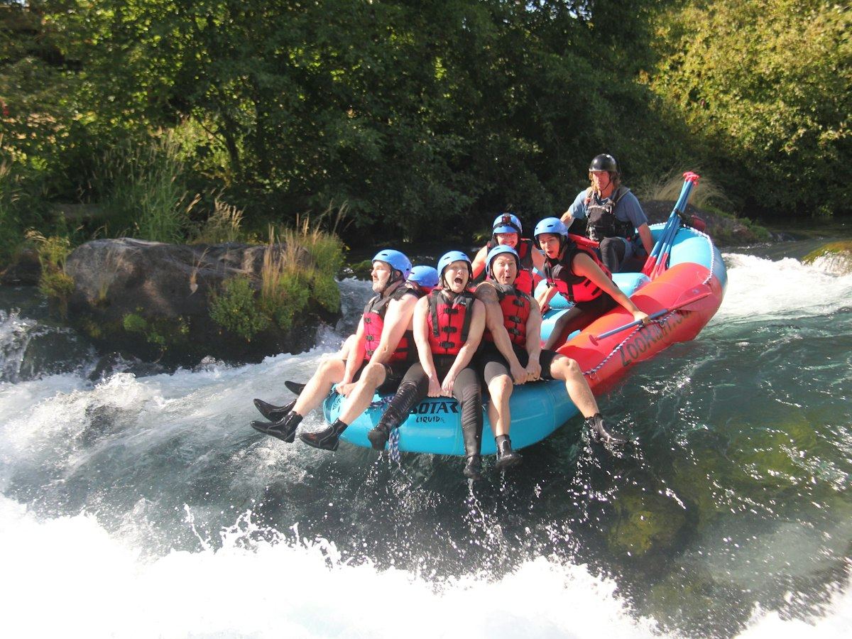 Group paddling a raft through a line of waves